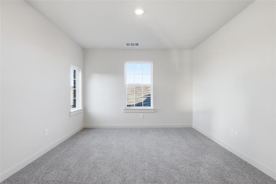 Spacious room featuring light gray carpeting, neutral wall paint, two windows with white trim, and a recessed ceiling light Spacious room featuring light gray carpeting, neutral wall paint, two windows with white trim, and a recessed ceiling light