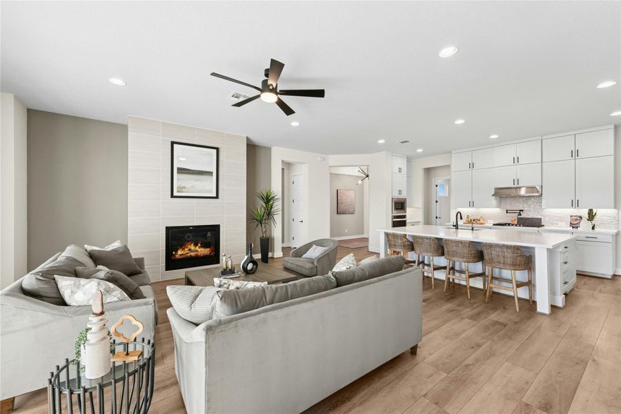 Living area featuring ceiling fan, light wood-style flooring, recessed lighting, and a fireplace Living area featuring ceiling fan, light wood-style flooring, recessed lighting, and a fireplace