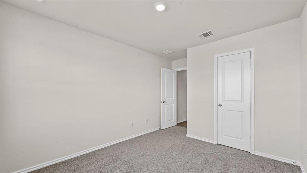 Neutral-toned room featuring a single overhead light fixture, light gray carpeting, white baseboards, and two white panel doors with silver hardware