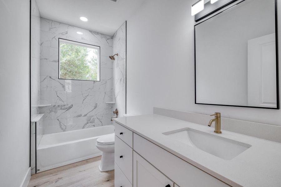 A well-lit bathroom features a modern vanity and a sleek shower-tub combination with elegant tile work. A well-lit bathroom features a modern vanity and a sleek shower-tub combination with elegant tile work.