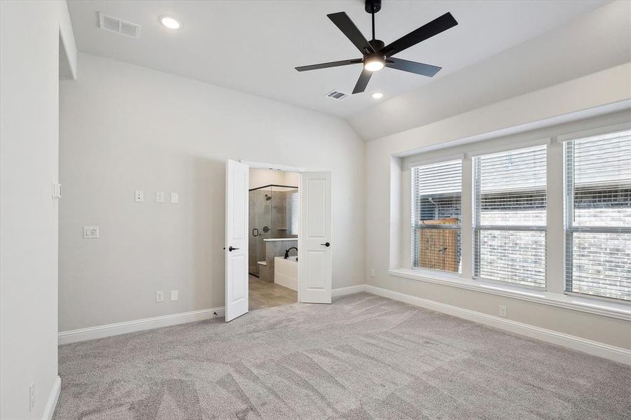 Unfurnished bedroom featuring light carpet, baseboards, vaulted ceiling, recessed lighting, and connected bathroom