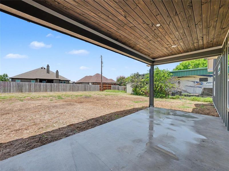 Covered concrete patio with a wood-finish ceiling, recessed lighting, and a metal support column Covered concrete patio with a wood-finish ceiling, recessed lighting, and a metal support column