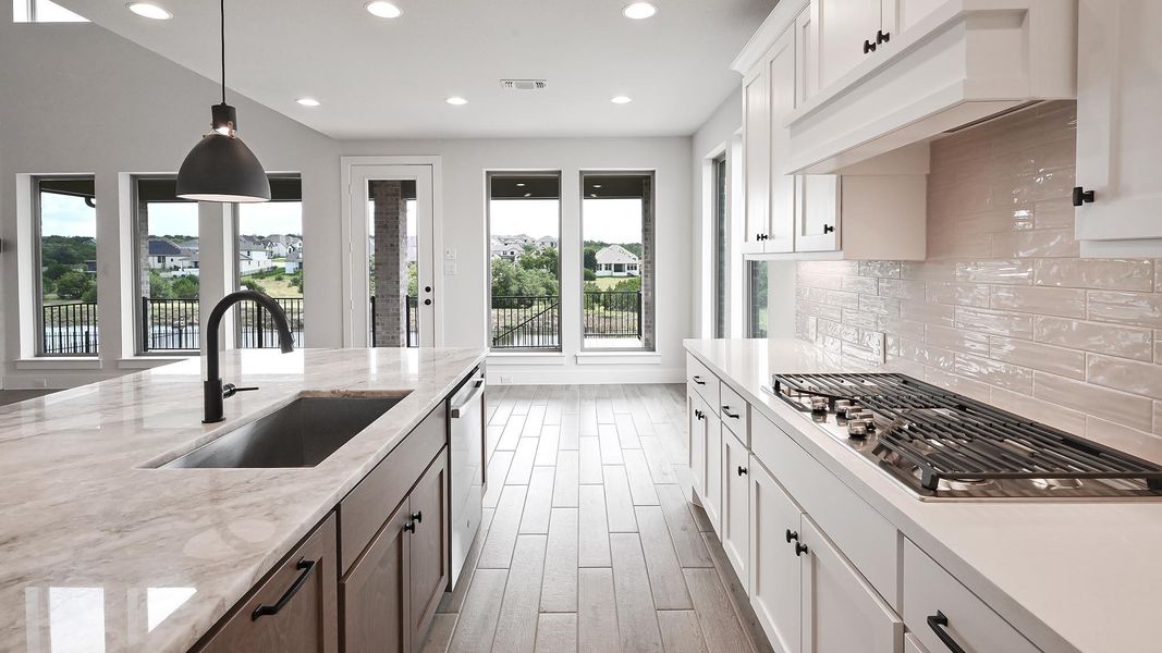 Kitchen with appliances with stainless steel finishes, premium range hood, recessed lighting, decorative backsplash, and decorative light fixtures Kitchen with appliances with stainless steel finishes, premium range hood, recessed lighting, decorative backsplash, and decorative light fixtures