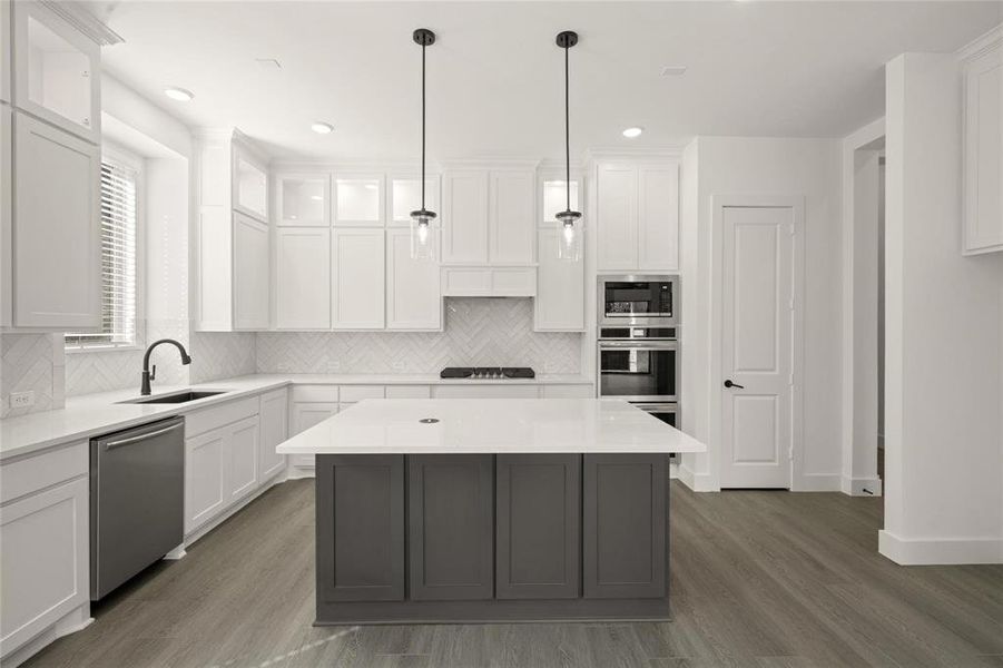 Dual tone kitchen featuring two tone color scheme, dark wood finished floors, stainless steel appliances, light stone countertops, and a center island