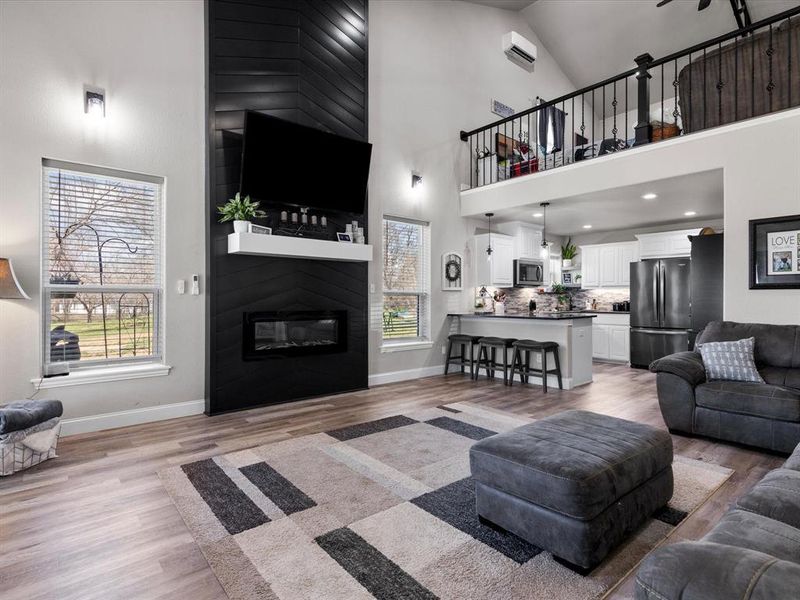 Living area featuring a healthy amount of sunlight, baseboards, a large fireplace, and light wood-style floors