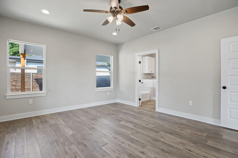 Unfurnished bedroom with wood finished floors, a ceiling fan, recessed lighting, and connected bathroom