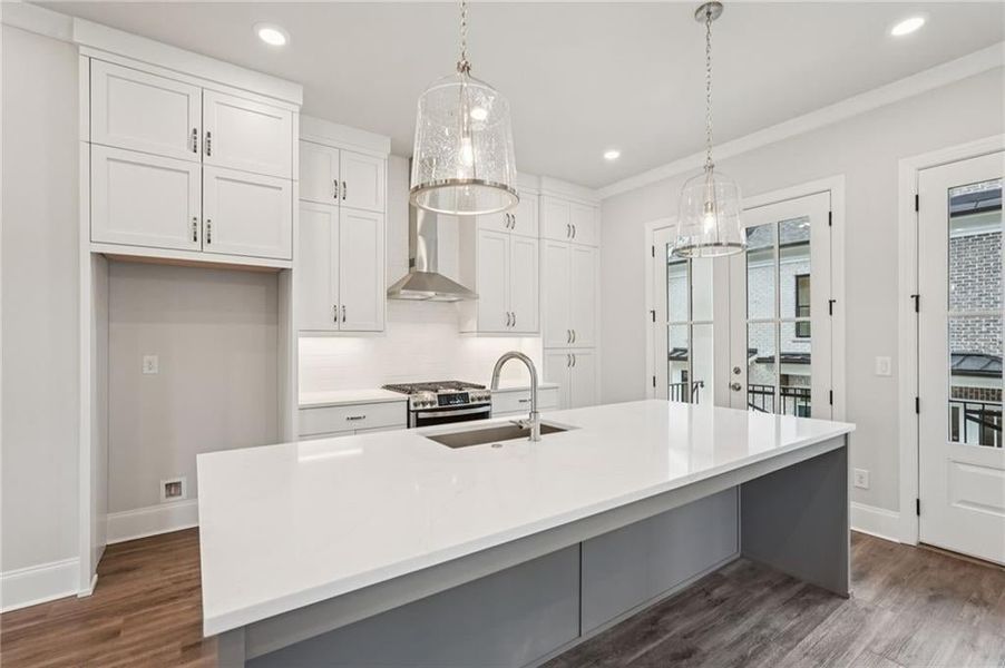 Kitchen with white cabinetry, hanging light fixtures, dark wood-style floors, gas range, and backsplash