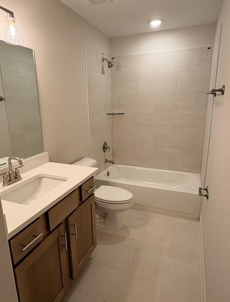 Full bathroom featuring a single vanity with stone-finish countertop, wood-finish cabinetry, and a full-width mirror