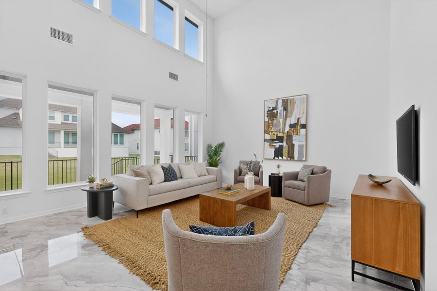 Two-story living area featuring high ceilings, multiple large windows, and reflective tile flooring