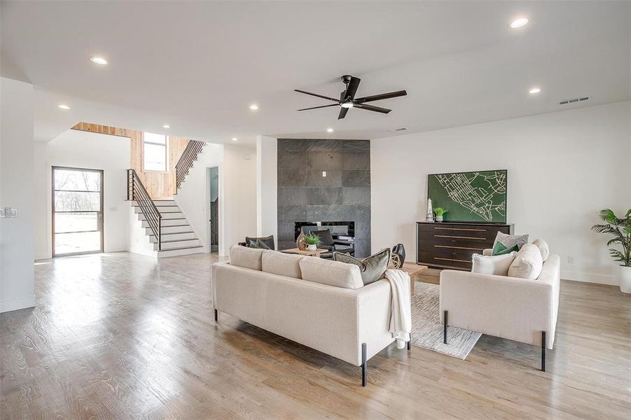 Living room featuring visible vents, a tile fireplace, stairway, light wood-type flooring, and recessed lighting