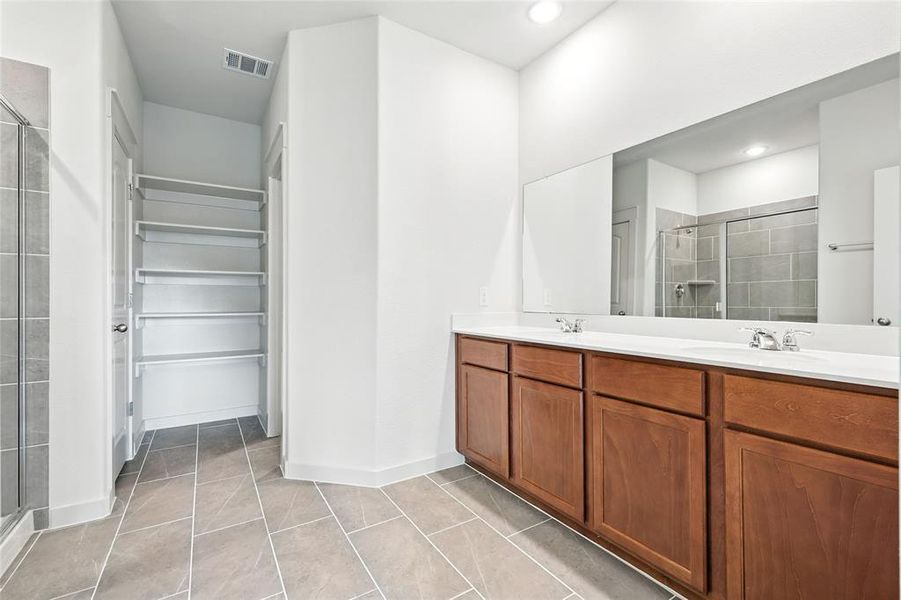 Bathroom featuring a stall shower, double vanity, light tile patterned flooring, a walk in closet, and recessed lighting Bathroom featuring a stall shower, double vanity, light tile patterned flooring, a walk in closet, and recessed lighting