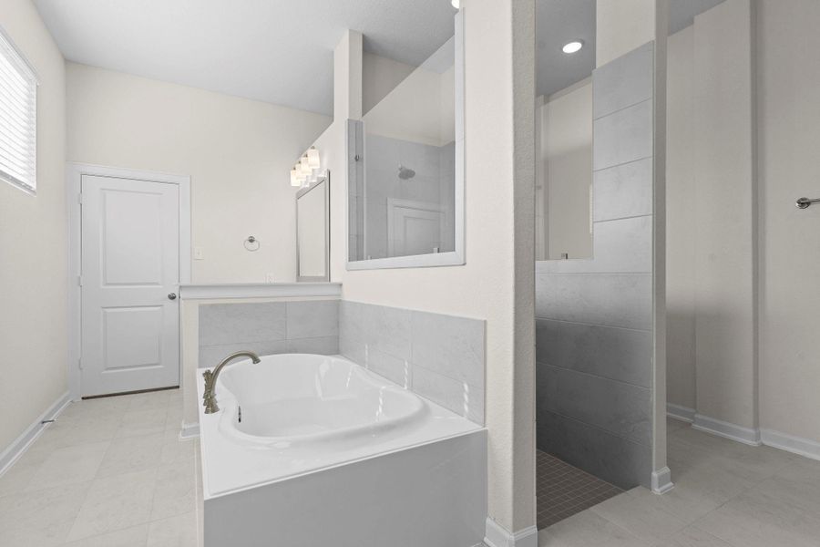 Spa-inspired primary bath with a deep soaking tub, separate glass shower, and natural light pouring in for a bright, refreshing atmosphere.  Around the corner pass the large shower you will discover the other private vanity!  This home was designed for two in this amazing bathroom!
