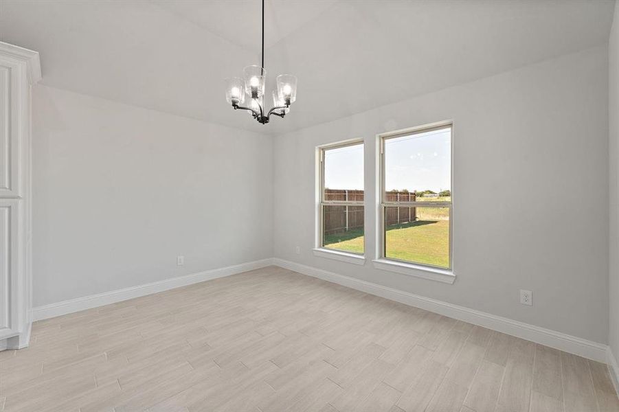 Unfurnished dining area with hanging lights, light wood-type flooring, and vaulted ceiling