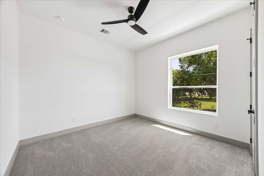Large windows, soft finishes, and a neutral palette create a versatile bedroom equally suited for family, guests, or a dedicated home office.