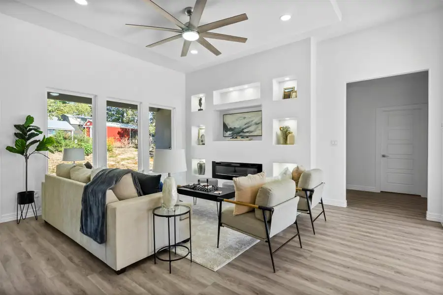 Living room with light wood-style flooring, built in features, recessed lighting, a glass covered fireplace, and ceiling fan