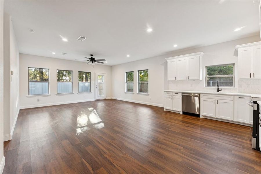 Unfurnished living room with recessed lighting, dark wood-type flooring, a ceiling fan, and plenty of natural light
