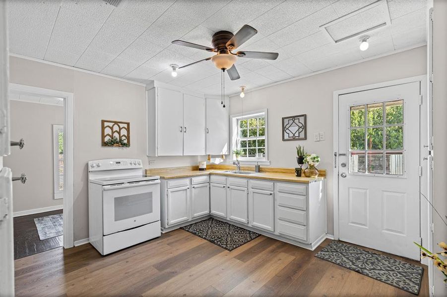 Kitchen with white electric range oven, white cabinetry, and healthy amount of natural light