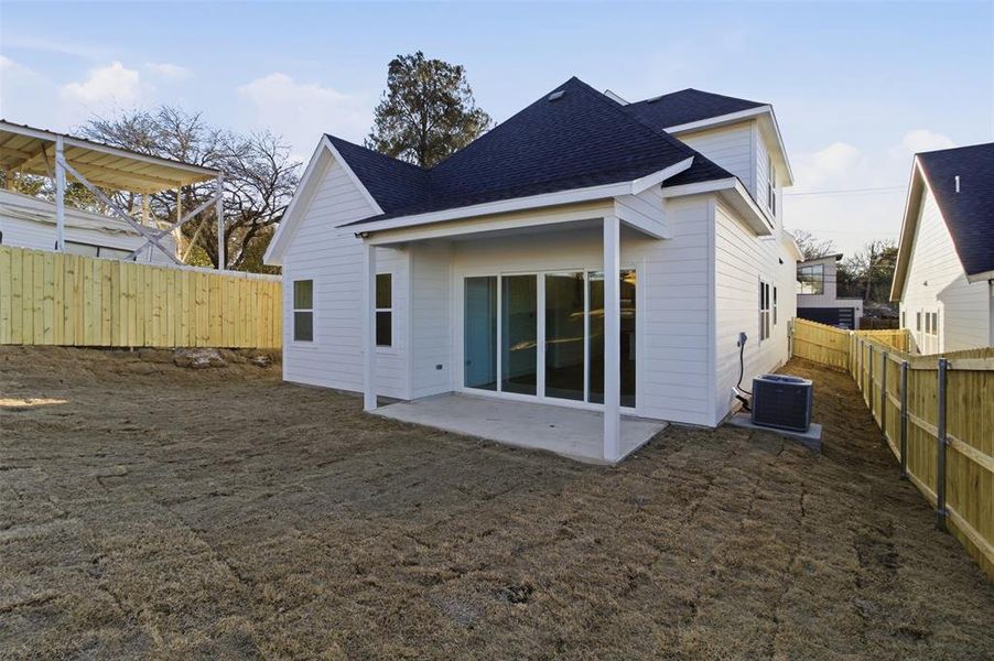 Rear view of house featuring a patio, roof with shingles, and a fenced backyard