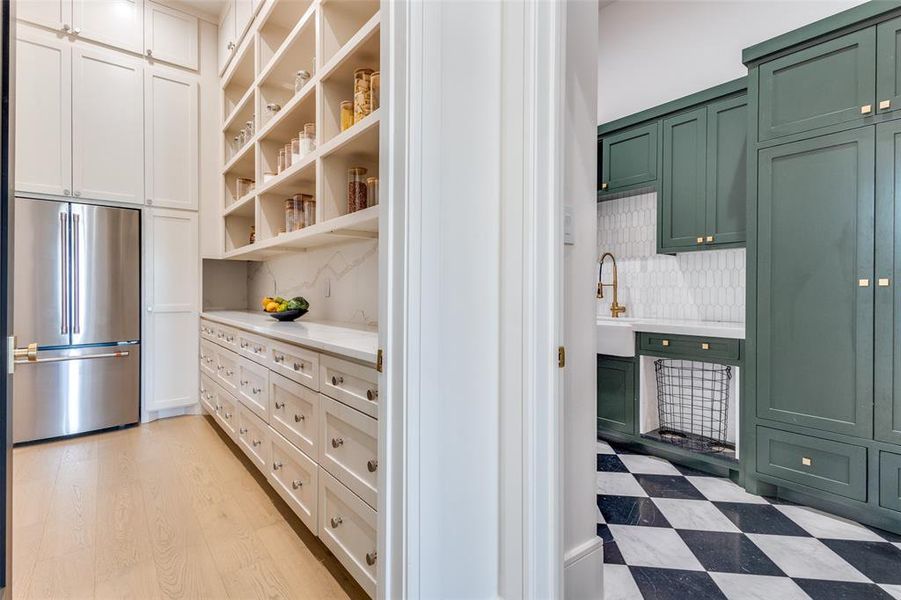 Kitchen featuring built in fridge, white cabinetry, tasteful backsplash, and light wood-type flooring