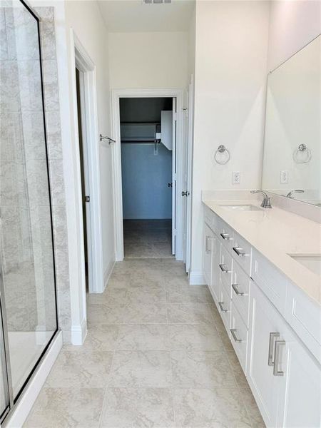 Bathroom featuring a sink, visible vents, a shower stall, double vanity, and a walk in closet