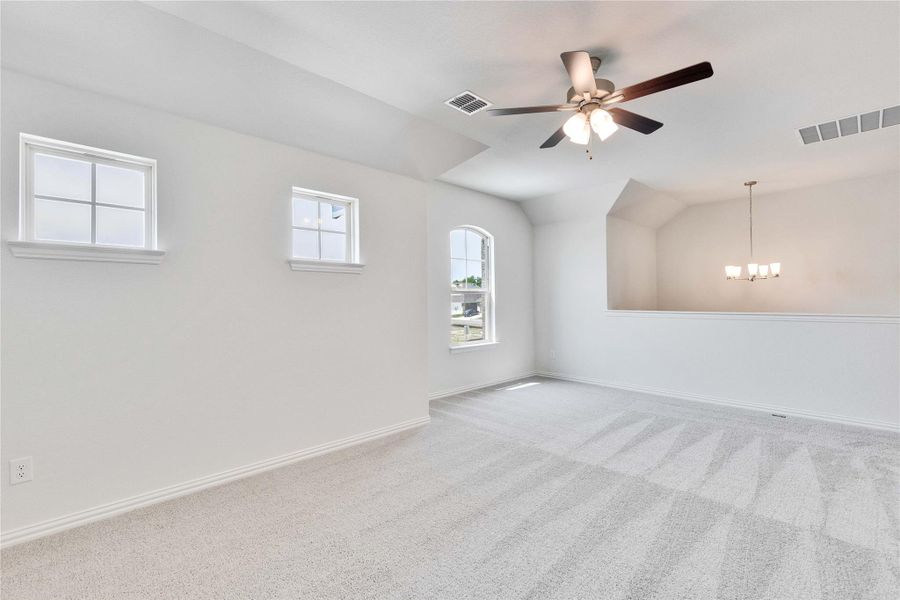 Carpeted empty room with a chandelier, baseboards, ceiling fan, and vaulted ceiling Carpeted empty room with a chandelier, baseboards, ceiling fan, and vaulted ceiling