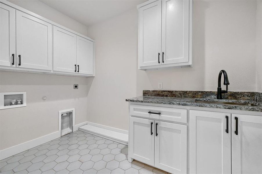 Clothes washing area with sink, cabinets, hookup for an electric dryer, hookup for a gas dryer, and light tile patterned floors