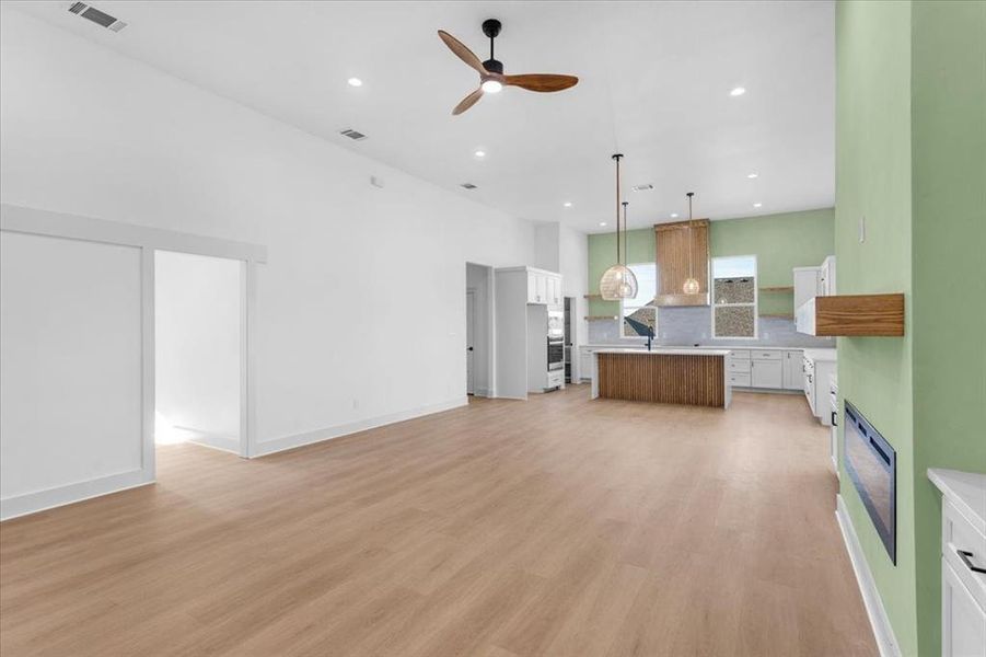 Kitchen featuring white cabinets, pendant lighting, light hardwood / wood-style floors, and a kitchen island