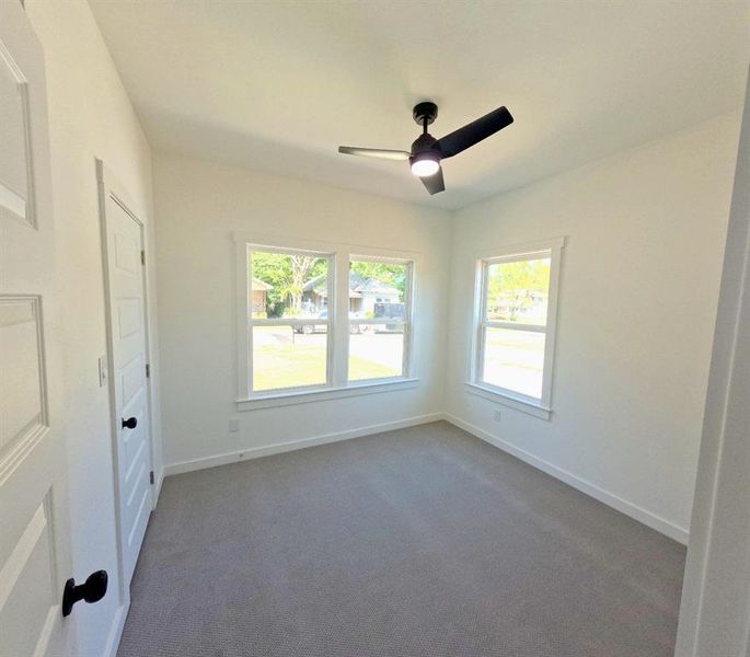 Unfurnished room with dark colored carpet, plenty of natural light, and ceiling fan Unfurnished room with dark colored carpet, plenty of natural light, and ceiling fan