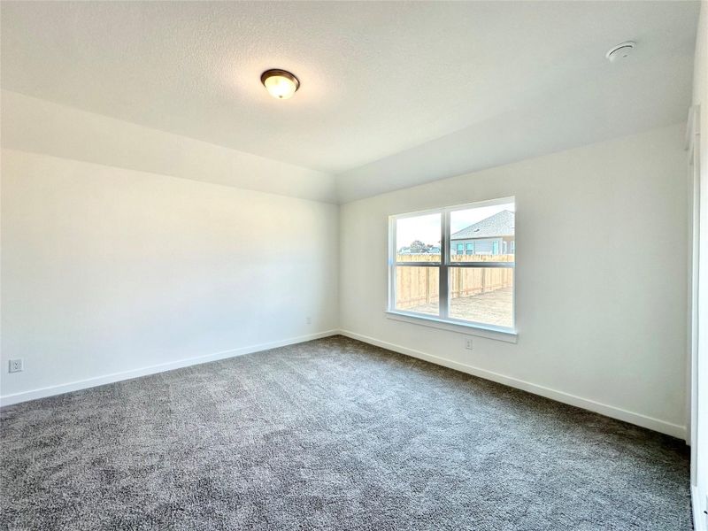 Carpeted spare room with a textured ceiling and vaulted ceiling