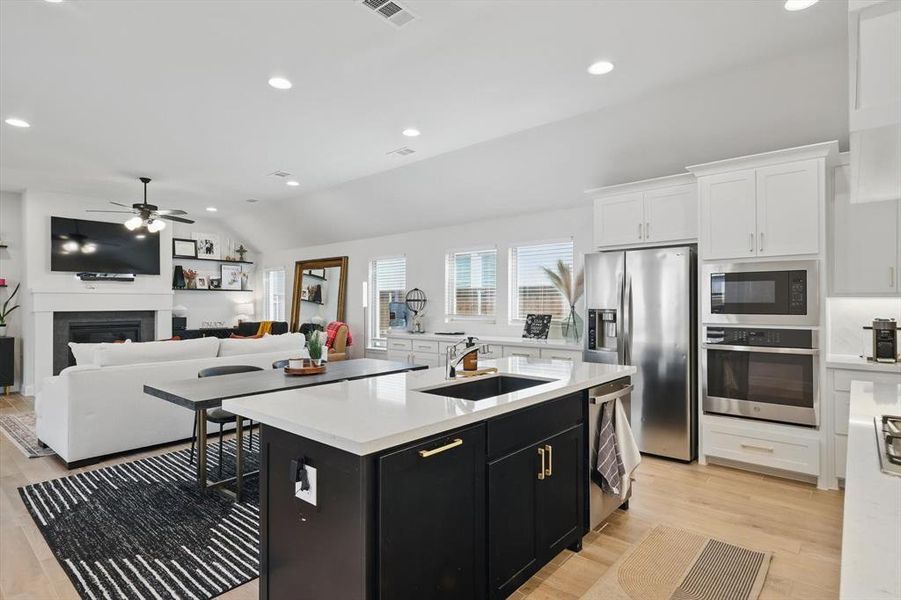 Kitchen featuring a sink, dark cabinetry, appliances with stainless steel finishes, white cabinets, and light countertops