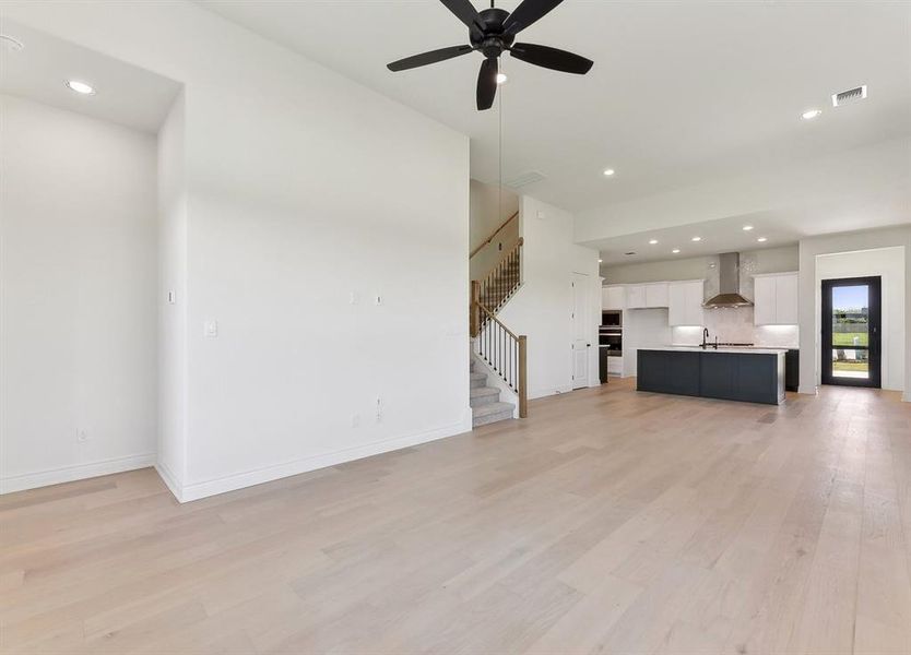 Spacious open-concept living area featuring light-colored flooring, a ceiling fan, and recessed lighting