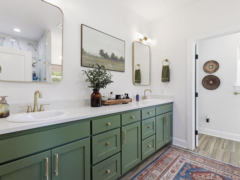 Full bath featuring double vanity and dark wood-type flooring