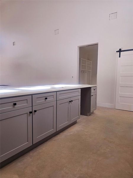 Kitchen featuring gray cabinetry, a sink, concrete floors, light countertops, and baseboards