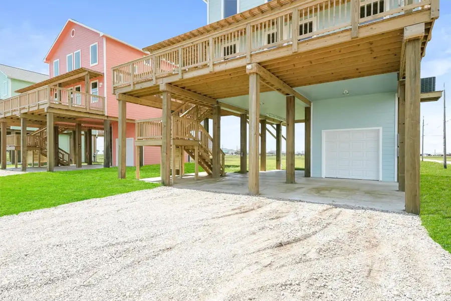 New construction home with wooden decks and staircases. Features a spacious covered area underneath, ideal for parking or storage, and a single-car garage. The exterior is painted in pastel colors, adding a coastal charm. New construction home with wooden decks and staircases. Features a spacious covered area underneath, ideal for parking or storage, and a single-car garage. The exterior is painted in pastel colors, adding a coastal charm.