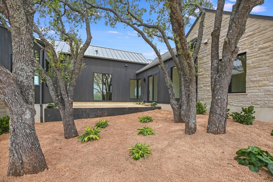 Mature trees and a clean gravel landscape frame the contemporary exterior of this home, featuring a spacious deck.