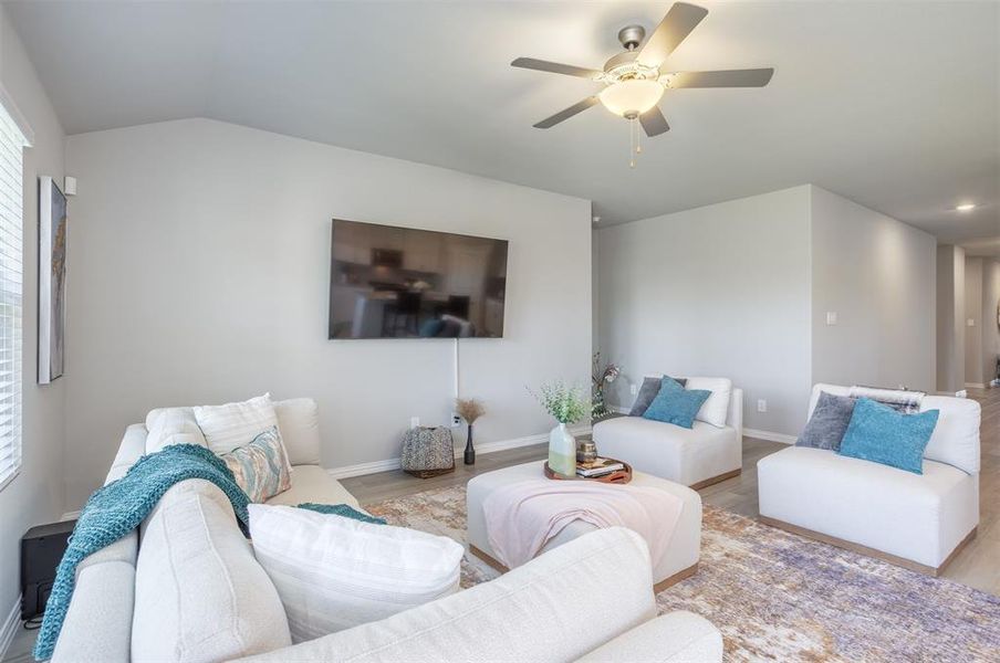Living area with ceiling fan, wood finished floors, and lofted ceiling Living area with ceiling fan, wood finished floors, and lofted ceiling