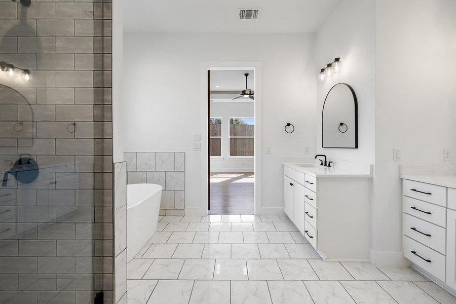 Full bathroom featuring vanity, a freestanding bath, a ceiling fan, and a tile shower
