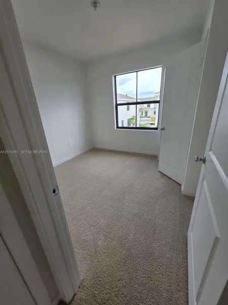 Room featuring neutral-tone carpeting, white walls, and a window with a black frame