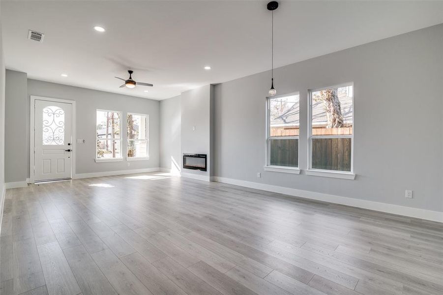 Unfurnished living room featuring ceiling fan, a healthy amount of sunlight, and light hardwood / wood-style flooring