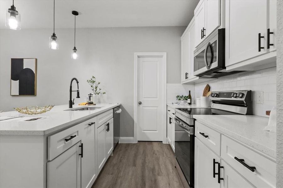 Kitchen featuring sink, hanging light fixtures, stainless steel appliances, tasteful backsplash, and white cabinets