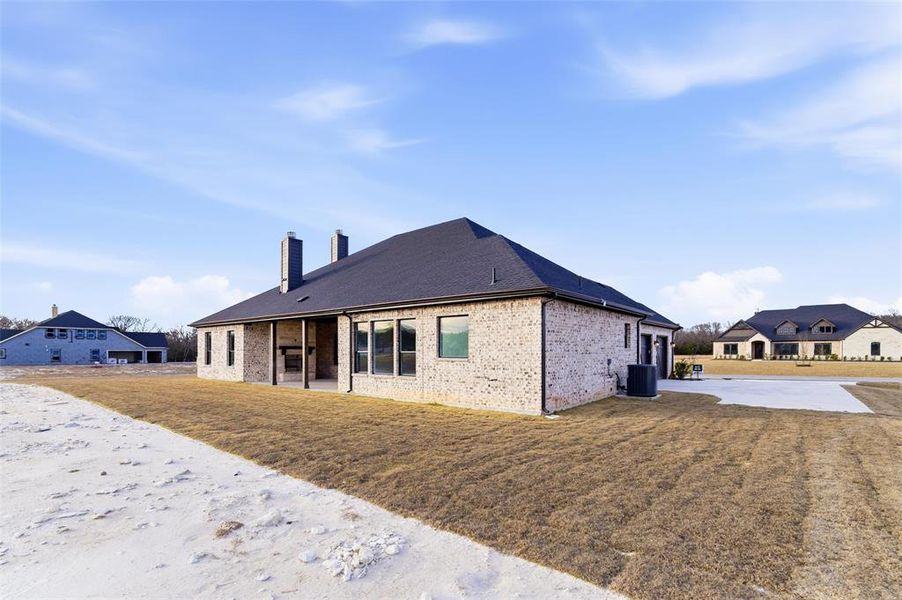 Back of house with a patio, brick siding, a lawn, and a chimney
