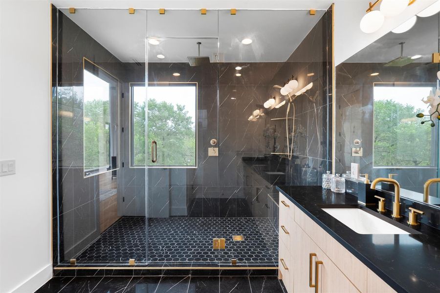 Luxurious bathroom featuring a spacious shower with black hexagonal floor tiles, a built-in bench, and large windows providing natural light