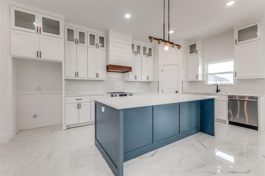 Kitchen with a center island, hanging light fixtures, tasteful backsplash, stainless steel dishwasher, and white cabinets