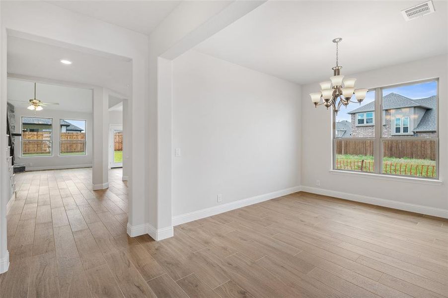 Unfurnished dining area featuring light wood-style flooring, ceiling fan, and a chandelier