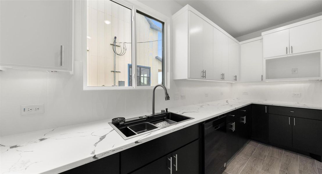 Kitchen featuring dark cabinetry, white cabinets, dishwasher, light wood-type flooring, and light stone counters