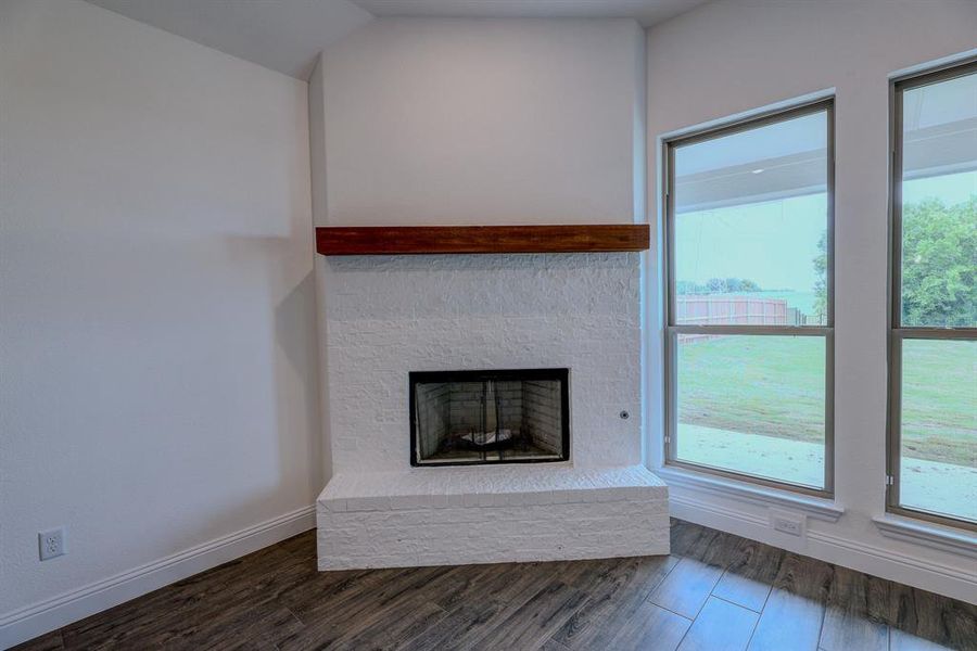 Detailed view of wood finished floors, a fireplace with raised hearth, and baseboards