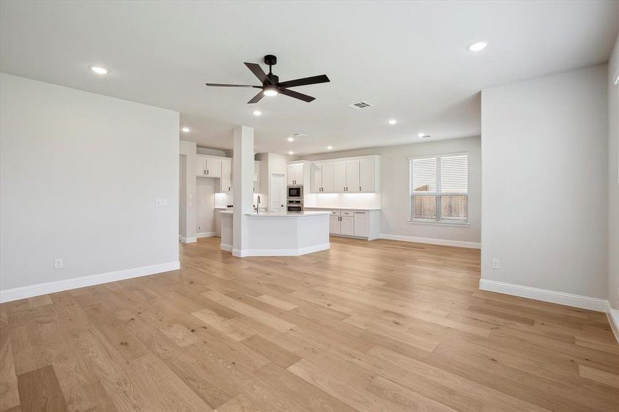 Unfurnished living room with a ceiling fan, light wood-style floors, baseboards, recessed lighting, and a sink