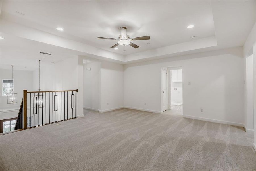 Spacious carpeted room featuring a ceiling fan, recessed lighting, and a tray ceiling