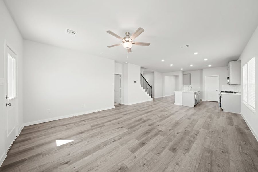 A large empty room with a wood floor and a ceiling fan.