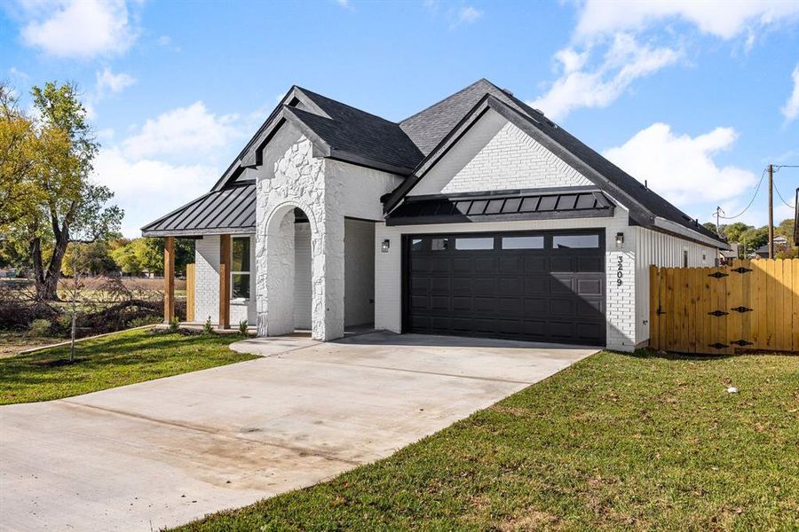 Modern farmhouse style home featuring a front yard and a garage